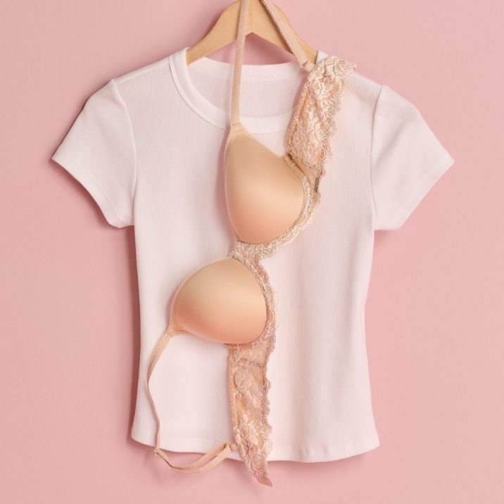 T-shirt blanc et soutien-gorge beige suspendus sur un ceintre