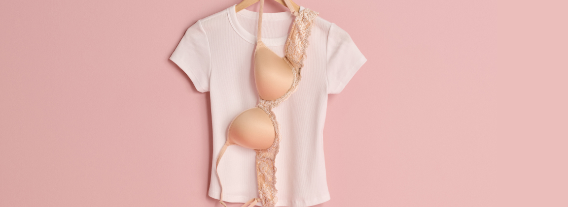 T-shirt blanc et soutien-gorge beige suspendus sur un ceintre
