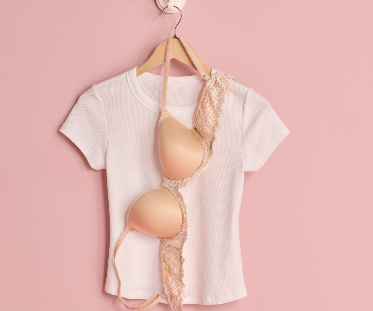 T-shirt blanc et soutien-gorge beige suspendus sur un ceintre