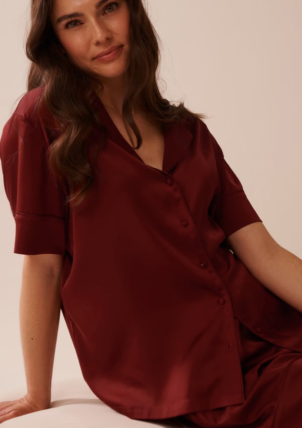 Model wearing a dark red satin set with shorts and short-sleeve top.