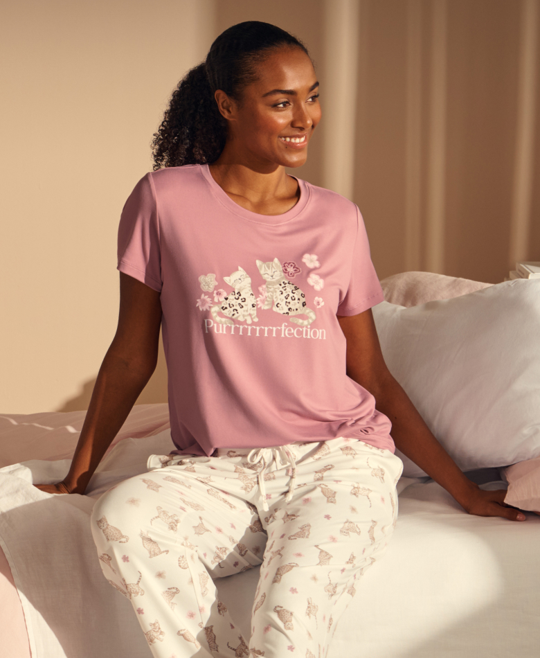 Model wearing soft pink pajamas with a cat print