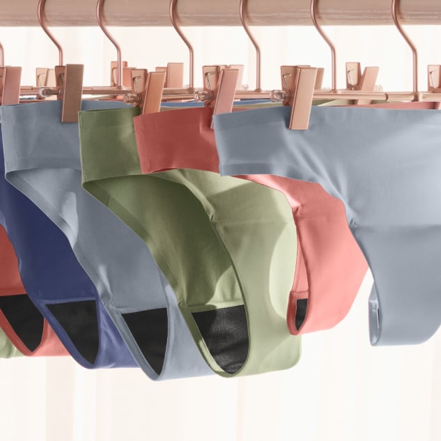 Several menstrual panties in various colors, suspended on hangers.