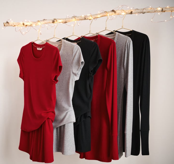 Ribbed modal pajamas in red, grey, and black hanging on a wooden rack.