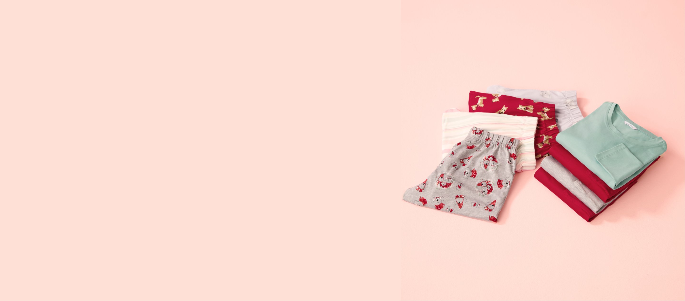 Several pajamas in various colors, folded on a pink background