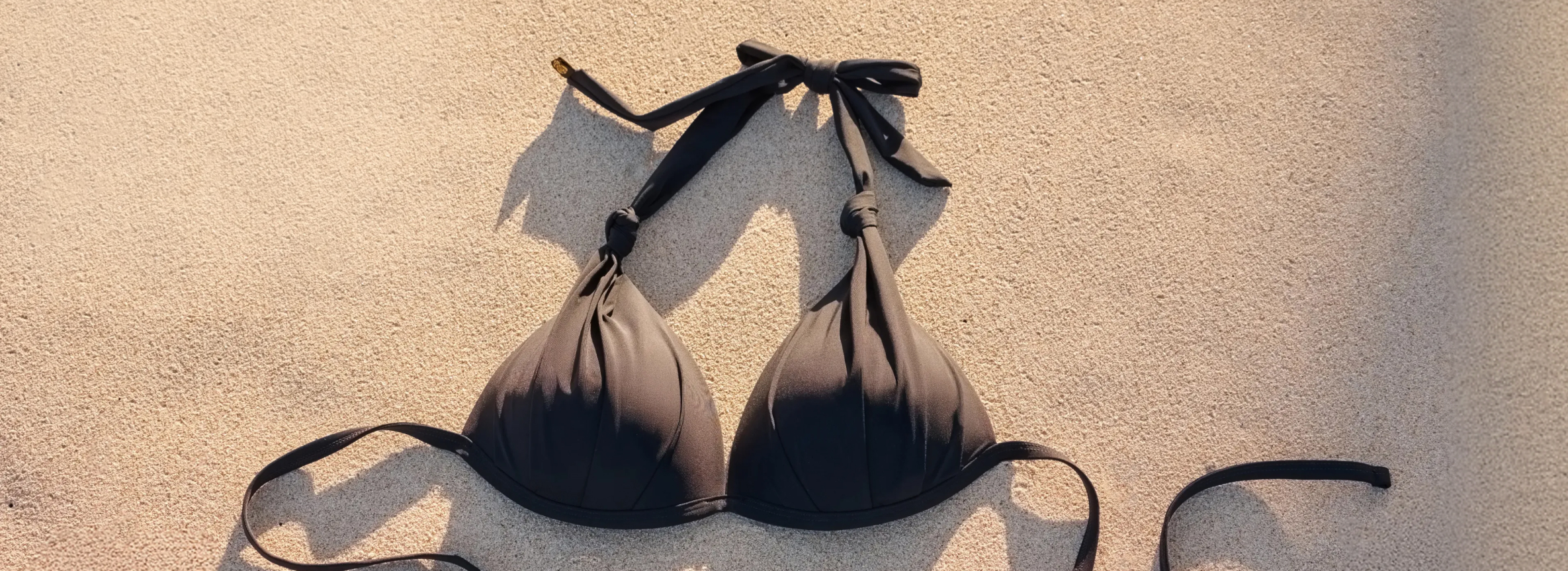 Black convertible bikini top resting on the sand