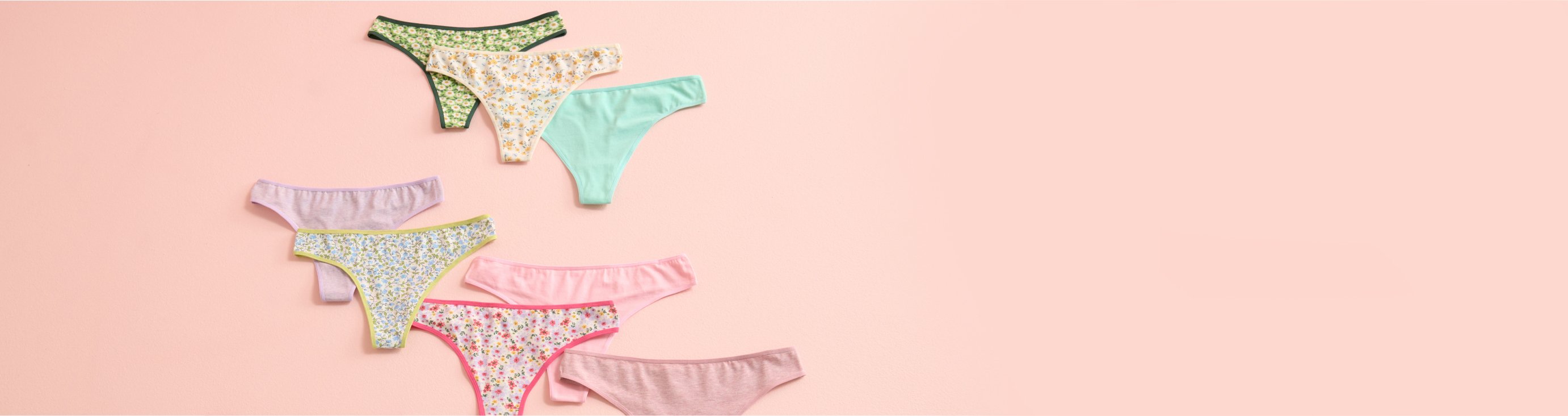 Panties in various colours and patterns laid out on a pink background.