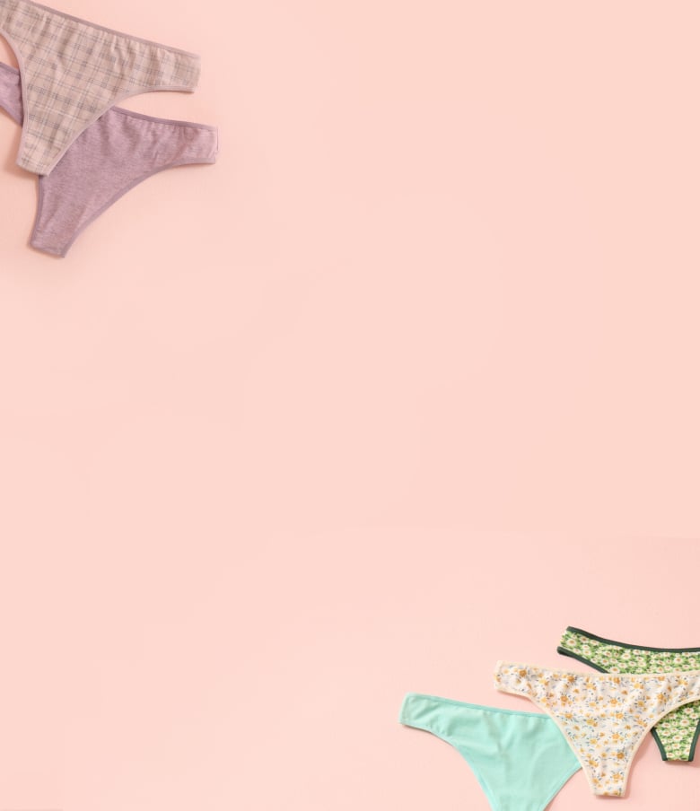 Panties in various colours and patterns laid out on a pink background.