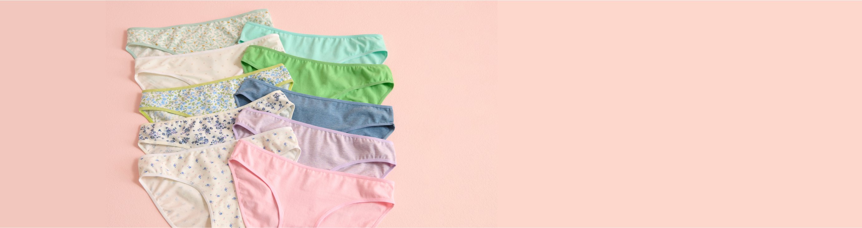 Panties in various colours and patterns laid out on a pink background.