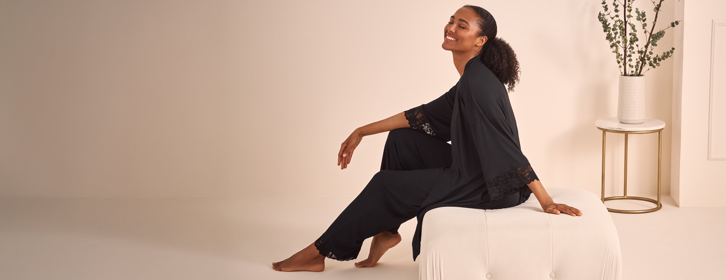 Model sitting in matching black kimono and pants, lace cuffs and hems.