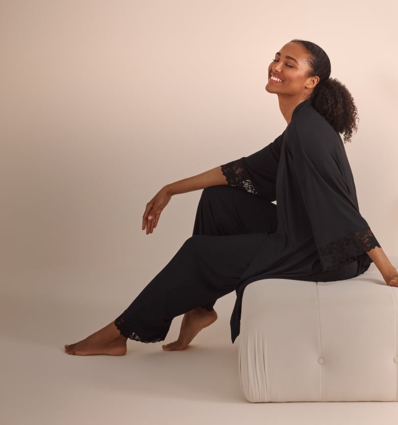 Model sitting in matching black kimono and pants, lace cuffs and hems.
