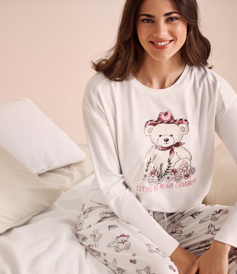 Model wearing a white pajama with cowboy bears, long-sleeve top and matching pants.
