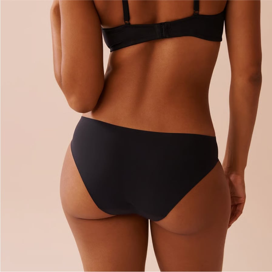 Vue arrière d’un mannequin portant une culotte menstruelle noire et un soutien-gorge noir.