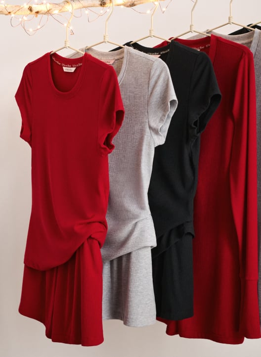 Ribbed modal sets in red, grey, and black hanging on hangers: short-sleeve tops, shorts, and rompers.