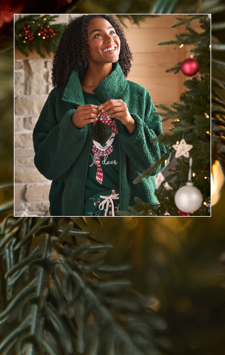 Model wearing a green pajama and cardigan with reindeer patterns.