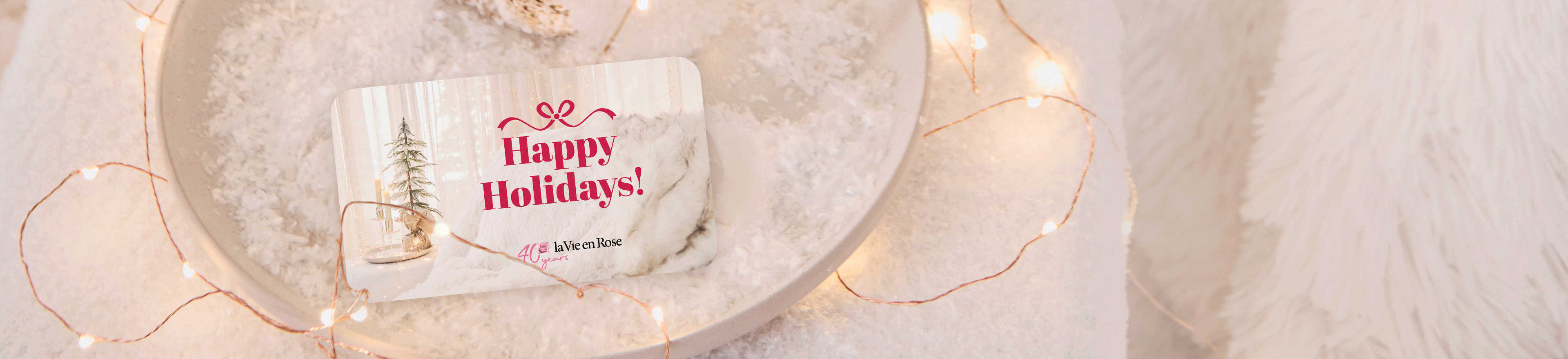 GIF of La Vie en Rose gift cards stacking on snowy background with festive lights