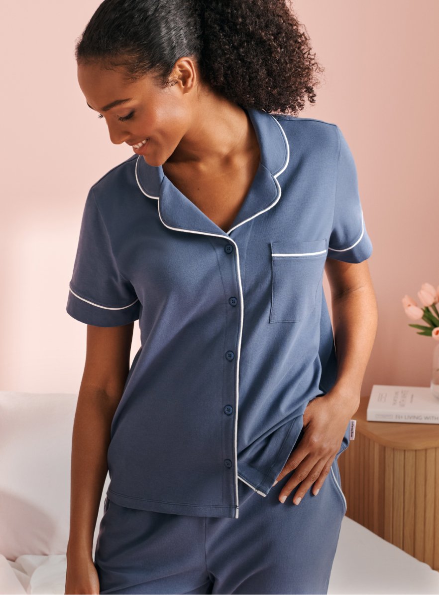 Banner linking to cotton pajama collection, model in blue set with short-sleeve shirt and matching pants.