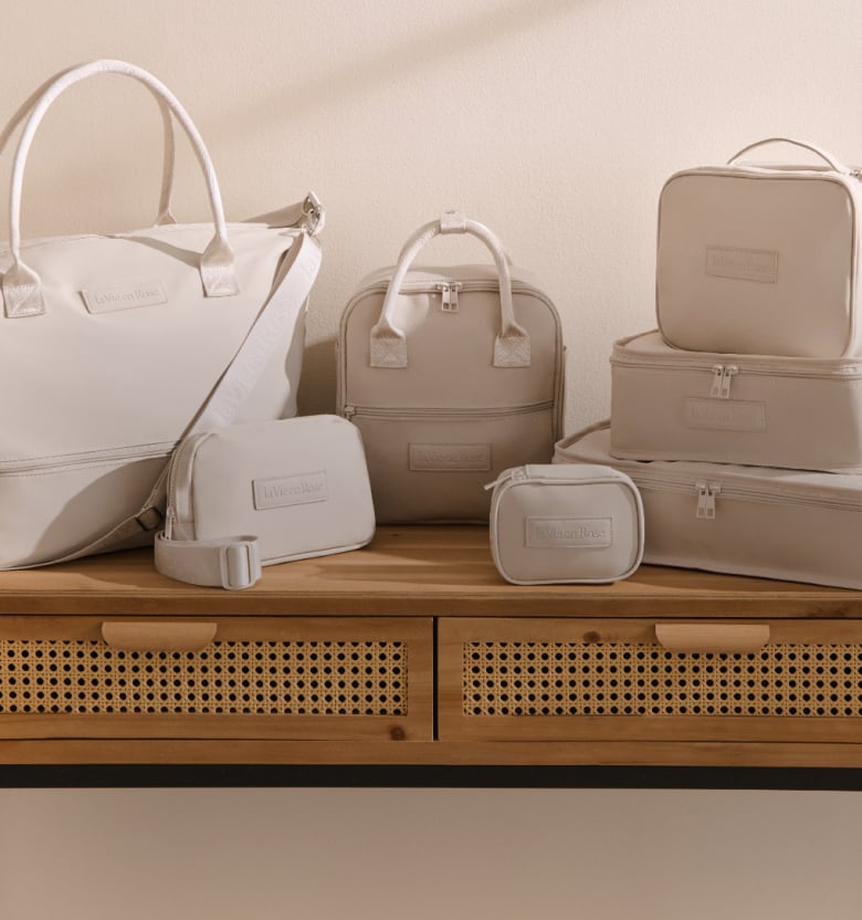 Seven beige travel accessories, including bags, pouches, and cases, placed on a table