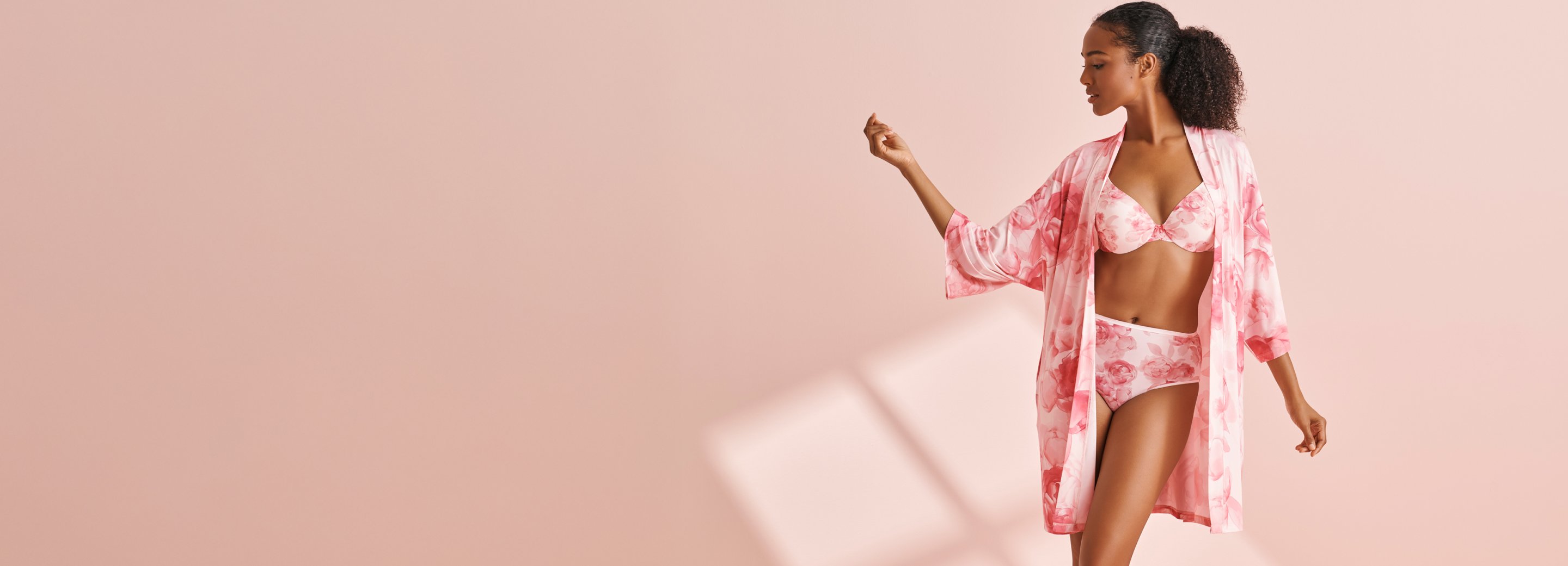 Model wearing a pink floral bra and panty set with a matching kimono, featured in a promotional banner