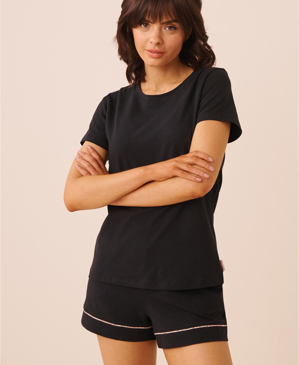 A model wearing black pajamas, consisting of shorts and a T-shirt