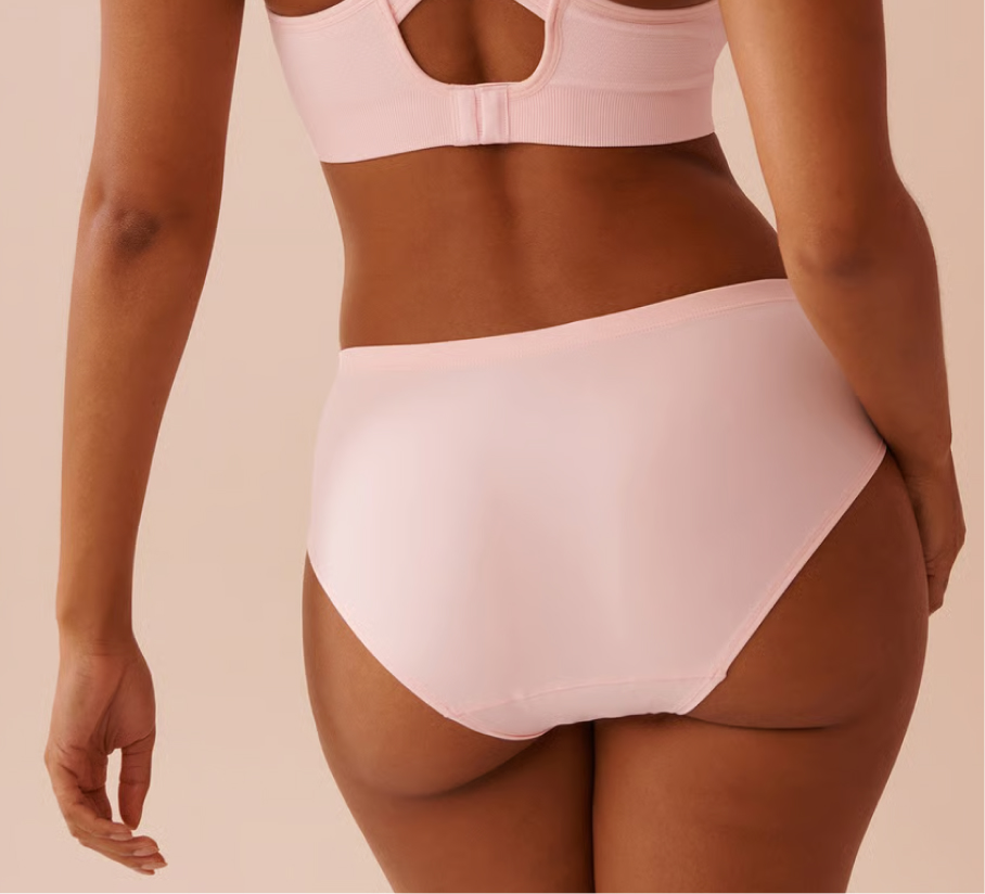 Three menstrual panties in red, black, and green displayed on a festive holiday setting.