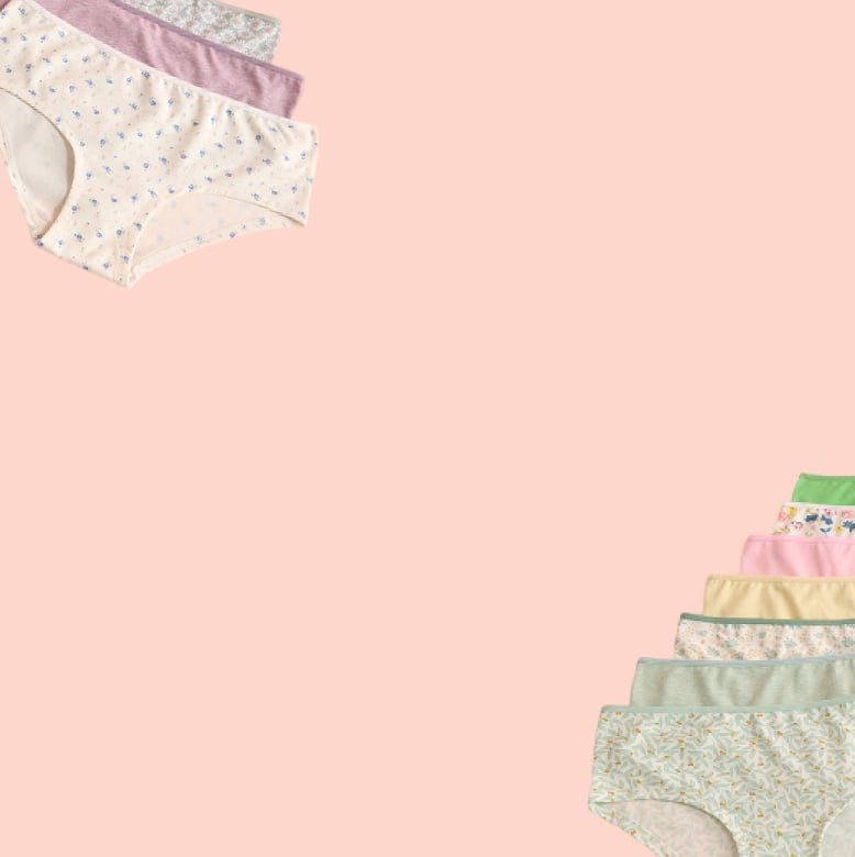 Panties in various colors and patterns laid out on a pink background.