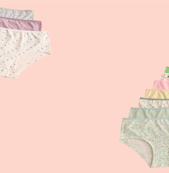 Panties in various colors and patterns laid out on a pink background.