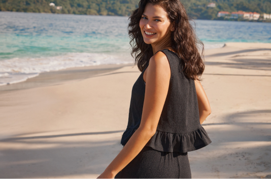 Model wearing a black ruffled tank top and black beach pants