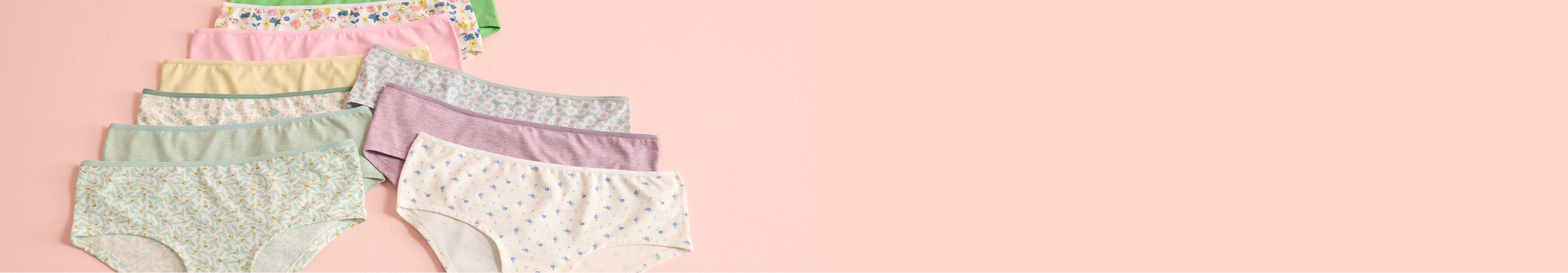 Panties in various colors and patterns laid out on a pink background.