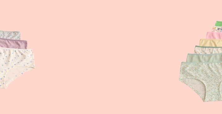 Panties in various colors and patterns laid out on a pink background.
