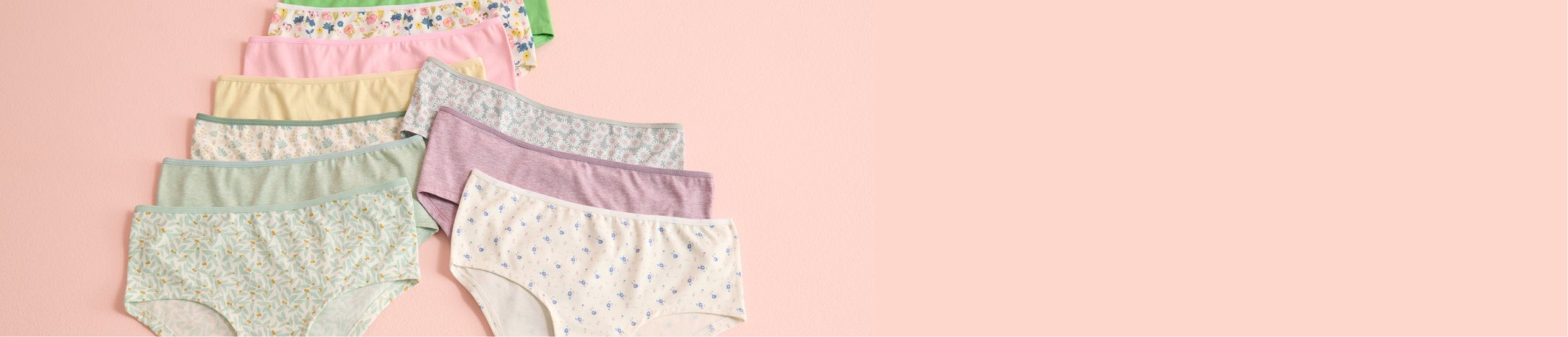 Panties in various colors and patterns laid out on a pink background.