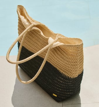 Black and beige straw beach tote by a poolside.