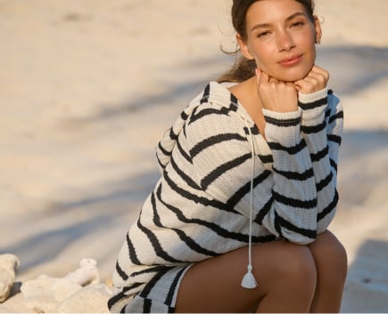 Model wearing a black and beige striped long-sleeve top and matching beach shorts.