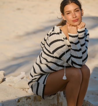 Model wearing a black and beige striped long-sleeve top and matching beach shorts.