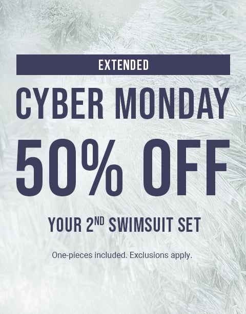 Model sitting by rocks wearing a floral print bikini top and bottom in red and turquoise.