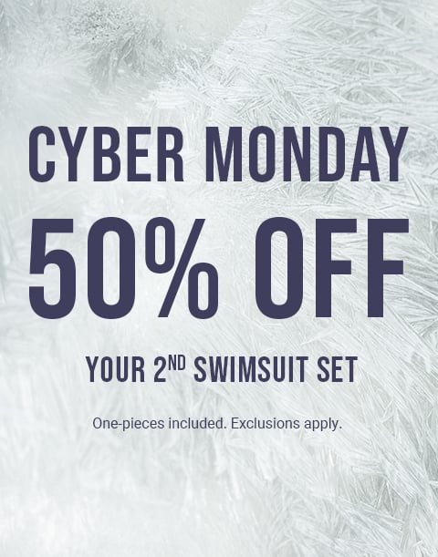 Model sitting by rocks wearing a floral print bikini top and bottom in red and turquoise.