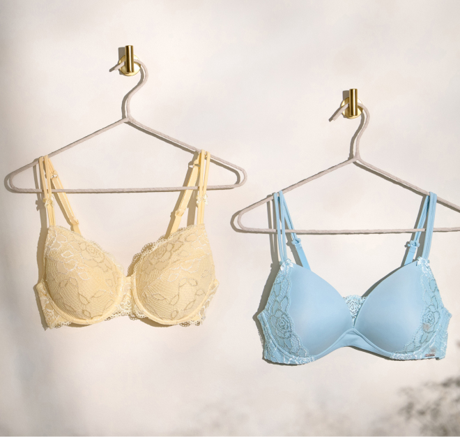 Two Muse mastectomy bras hanging on hangers. One is yellow, the other is blue.