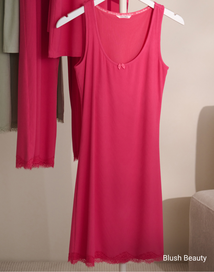 Model seen from behind wearing a textured pink bodysuit with an open back and a large bow at the waist.