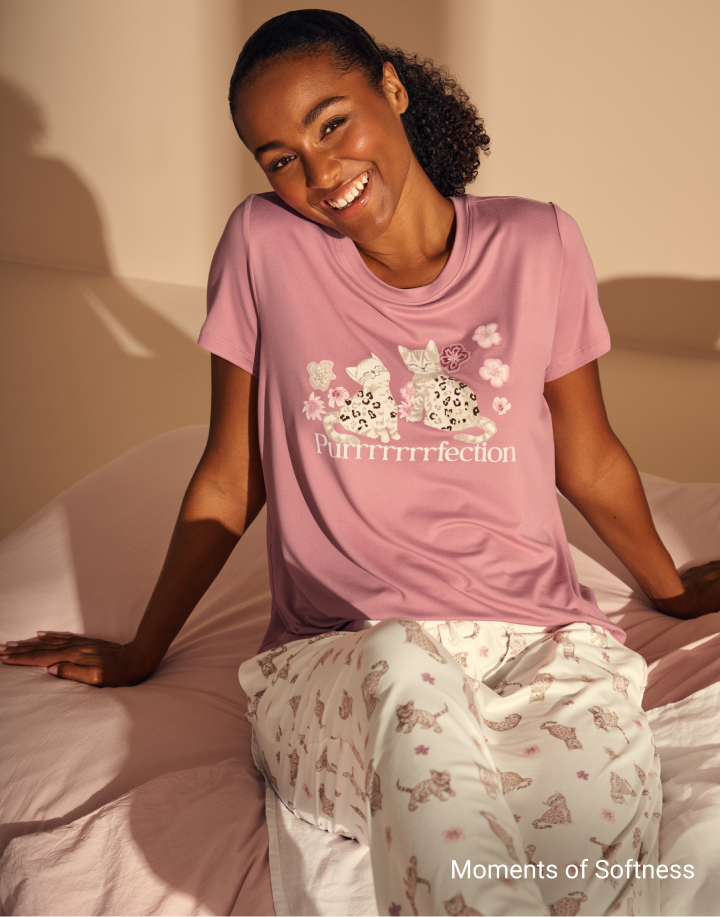 Model wearing soft pink pajamas with a cat print